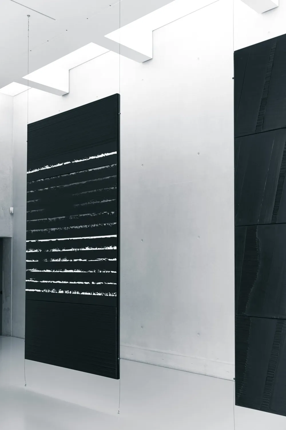 Dark panels hung against pale concrete walls in a spare, well-ordered interior.